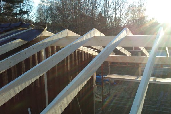 Takstolar och bärande konstruktion under pågående byggnation i solnedgång
